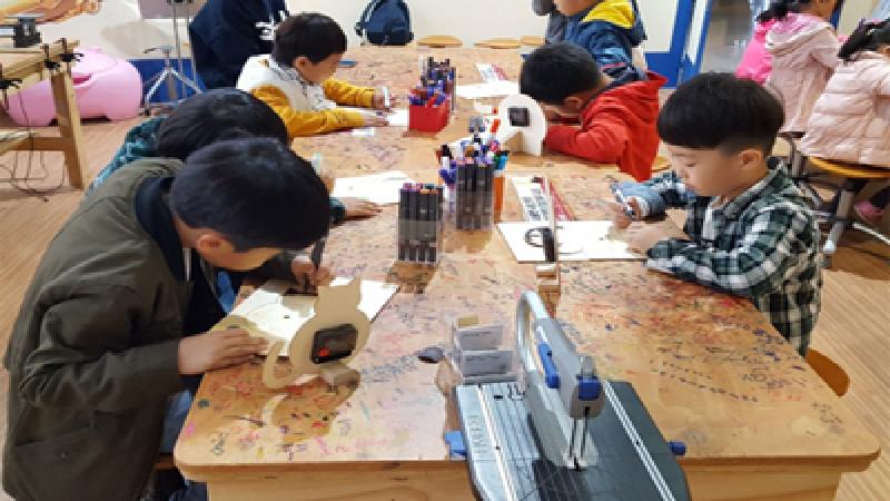  창의공작소에서 목공시계 도안을 색칠하는 교육생 사진